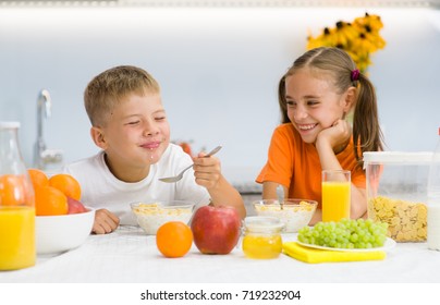 Happy children breakfast with cornflakes and milk in the kitchen
