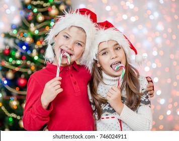 Happy Children In Christmas Caps Eating Candy Canes