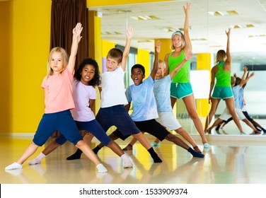 Happy Children Dancing Synchronous Group Choreography With Female Coach In Dance Hall