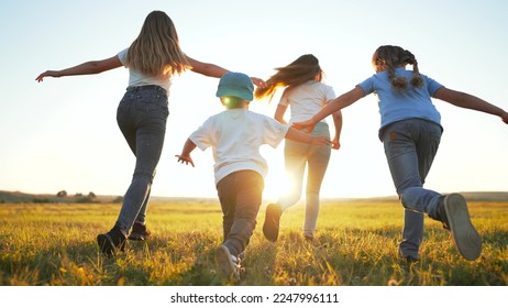 Happy children with dog run together on green field of park at sunset. Rear view of children running across field. crowd of children with dog run along green grass in summer park. Happy childhood. - Powered by Shutterstock