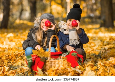 Happy children eating red apple while walking in autumn park