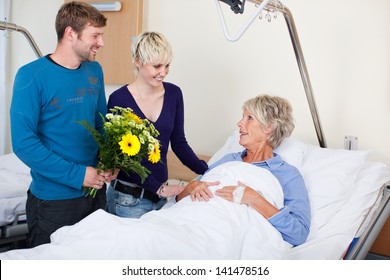 Happy children with flowers visiting mother in hospital
