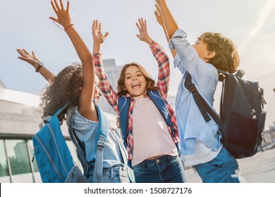 Happy Children With Hands Up Standing Near School Outdoors