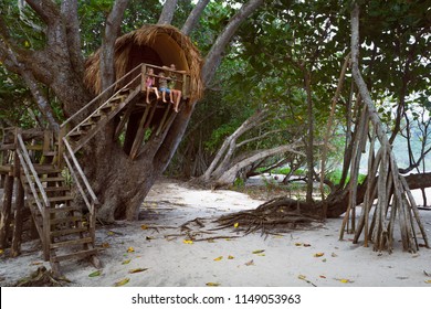 Happy children have fun on beach walk. Kids, young mother sit on balcony edge of tree house dangling legs, look at sea through jungle. Vacation lifestyle, outdoor travel activity in family summer camp - Powered by Shutterstock