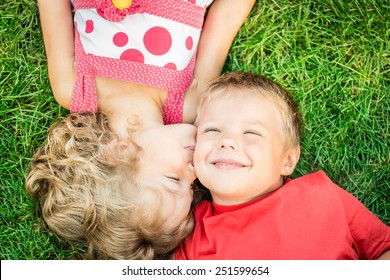 Happy children having fun outdoors. Kids playing in spring park. Boy and girl lying on green grass