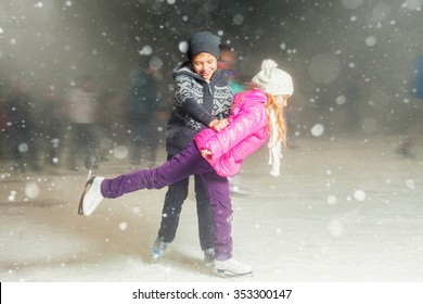 Happy Children Ice Skating At Ice Rink Outdoor, Figure Skating, At Winter Snowy Night, Sport And Healthy Lifestyle, Ice Skating At Holland. Funny Kids, Boy And Girl, Sister And Brother. Family