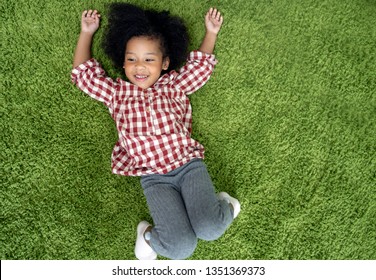 Happy Children Kids Smiling And Laying On Green Carpet Floor In Living Room At Home.