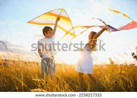 Happy children launch a kite in the field at sunset. Little boy and girl on summer vacation