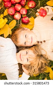 Happy Children Lying On Fall Leaves. Funny Kids Outdoors In Autumn Park