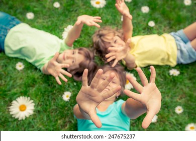 Happy Children Lying On Grass. Funny Kids Playing In Park. Beautiful Spring Flowers. Top View