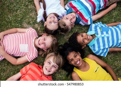 Happy children lying on grass in park - Powered by Shutterstock