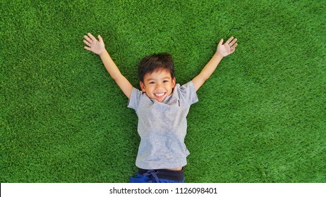 Happy children lying on green grass outdoors in spring park. - Powered by Shutterstock