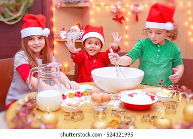 Happy Children Making Christmas Cookies At Home, Cute Little Kids Wearing Red Santa Claus Hats, Preparing Festive Sweets, Traditional Celebration Of Winter Holidays