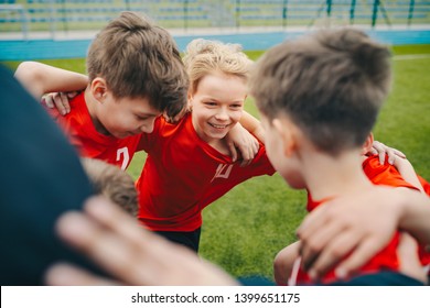 Happy Children Making Sport. Group Of Happy Boys Making Sports Huddle. Smiling Kids Standing Together With Coach On Grass Sports Field. Boys Talking With Coach Before The Football Game