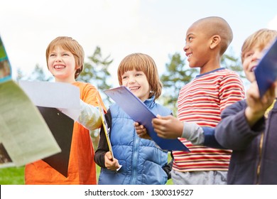 Happy Children On A Treasure Hunt As A Scavenger Hunt In Nature With Clipboard