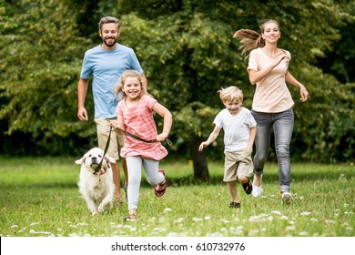 Happy children and parents with dog as family running in the nature - Shutterstock ID 610732976