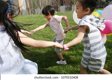 Happy Children Play On The Grass