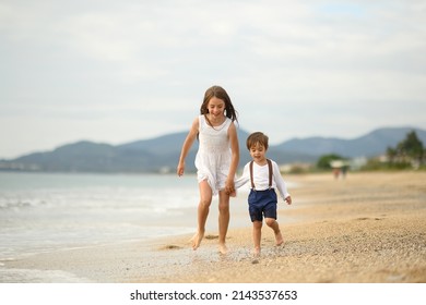 Happy children play on the sea. Happy boy and girl are playing with sea waves. Beautiful children on the sea beach. Happy childhood. Vacation at sea with children. - Shutterstock ID 2143537653