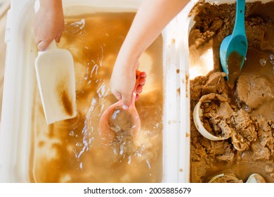 Happy Children Play With Sand And Water In Sensory Baskets On The Outdoor Sensory Table, Sensory Early Development, Montessori. Baby Hands With Sand And Water Close Up, Soft Focus