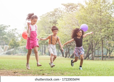 happy children playing with colorful toy balloons outdoors. Kid having fun in green spring field against blue sky background. happy multi-ethnic children playing. freedom and imagination concept.