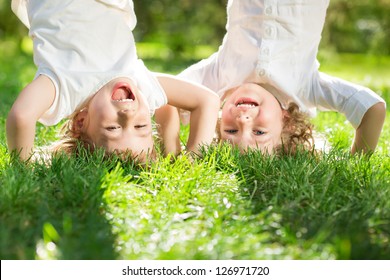 Happy children playing head over heels on green grass in spring park