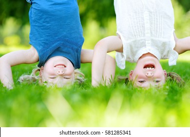 Happy children playing head over heels on green grass in spring park 