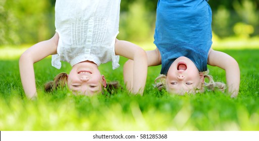 Happy children playing head over heels on green grass in spring park 