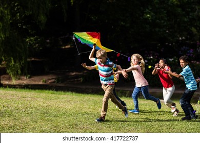 Happy children playing with a kite in the park - Powered by Shutterstock