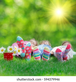 Happy Children Playing Outdoors. Kids Having Fun In Spring Park. Friends Lying On Green Grass