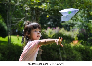 Happy children playing with paper airplane in the summer garden. Cute little girl throwing paper planes in the park. happy childhood concept.