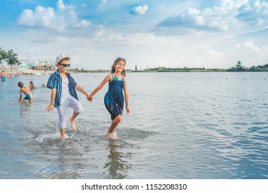 Happy Children Playing In The Sea. Kids Having Fun Outdoors. Summer Vacation And Healthy Lifestyle Concept