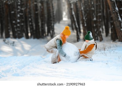 Happy children playing with snow in winter outdoors. Children sculpt and make a snow globe. Family on vacation in winter. - Powered by Shutterstock