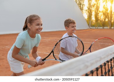 Happy children playing tennis on court outdoors - Powered by Shutterstock