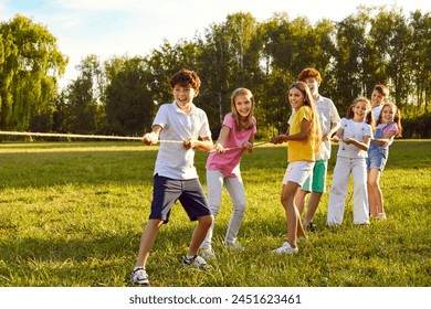 Happy children playing together in tug-of-war with a rope in the park on summer holidays in nature. Smiling school kids having fun on the green grass outdoors spending time in the camp. - Powered by Shutterstock