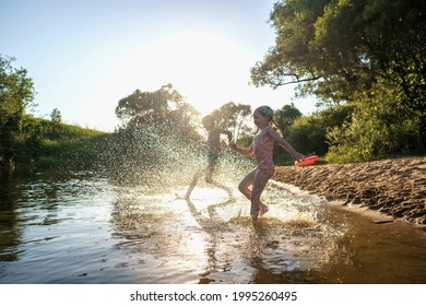 Happy children run from the shore into the water. Summer children's vacation on shore of a lake or river. boy and girl jump into water, swim and splash around at sunset. Active holidays. Dynamic image - Powered by Shutterstock