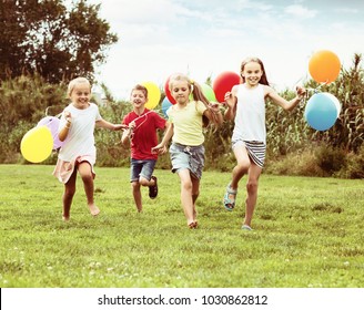 Happy Children Running With Balloons In Hands On Summer Sunny Field