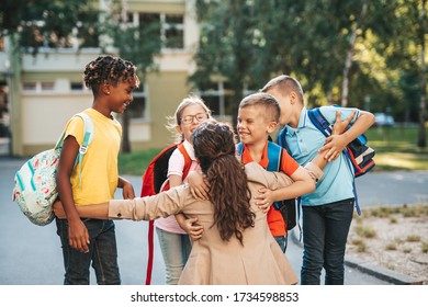Happy children running into hug of their teacher.
