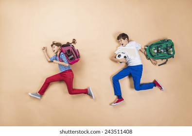 Happy Children Running To School In A Hurry. Studio Shot On A Beige Background.