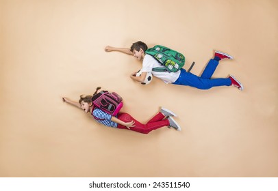 Happy Children Running To School In A Hurry. Studio Shot On A Beige Background.