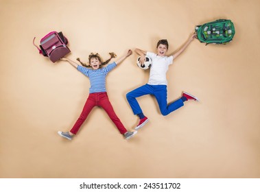 Happy Children Running To School In A Hurry. Studio Shot On A Beige Background.