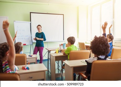 Happy Children Sitting In Class And Classmates In The Background, Doing Schoolwork