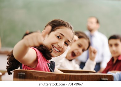 Happy children smiling and laughing in the classroom, showing thumb up, successful pupils and teacher - Powered by Shutterstock