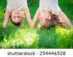 Happy children standing upside down on green grass. Smiling kids having fun in spring park. Healthy lifestyle concept