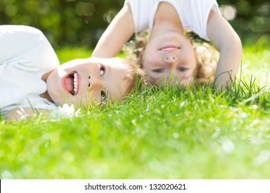 Happy children standing upside down on green grass. Boy and girl in spring park. Healthy lifestyles concept. - Powered by Shutterstock