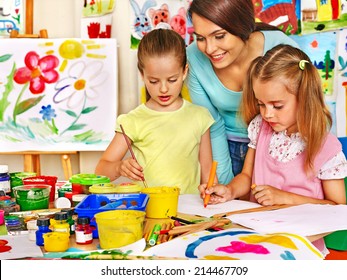 Happy children with teacher painting.