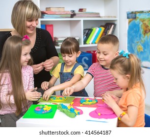Happy children with teacher playing with color play dough at classroom - Shutterstock ID 414564187