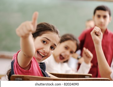 Happy children with their teacher in classroom, doing schoolwork