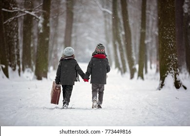 Happy Children In A Winter Park, Playing Together With A Sledge While Snowing. Childhood Happiness Concept