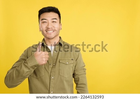Happy chinese man gesturing agreement raising a thumb up