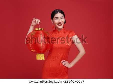 Happy Chinese new year. Asian woman wearing traditional cheongsam qipao dress holding Chinese lanterns isolated on red background.